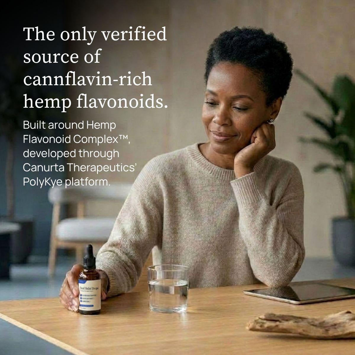 A woman sits at a wooden table holding a bottle of Dual Relief™ Drops, with a glass of water and a tablet nearby. Large text on the left reads, 'The only verified source of cannflavin-rich hemp flavonoids. Built around Hemp Flavonoid Complex™, developed through Canurta Therapeutics PolyKye Platform.'